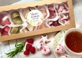 Box of Shore & Stem Beverage Gems, a teacup of tea, and raspberries and Rosemary on a marble surface.