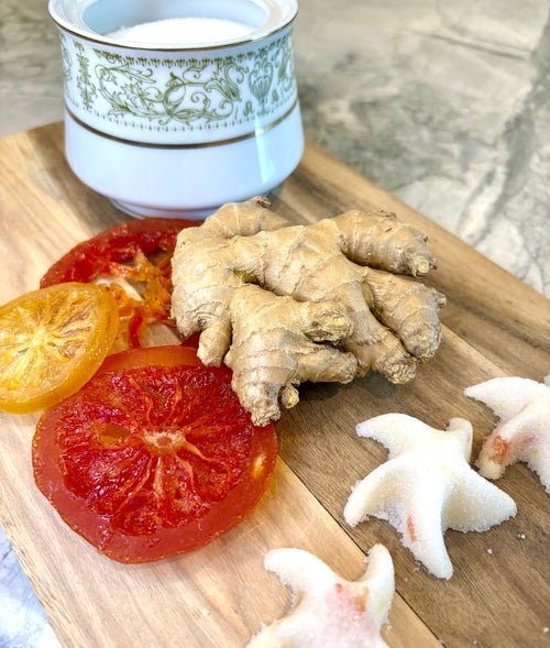 Ginger root with sliced grapefruit and sugar gems on a wooden board.